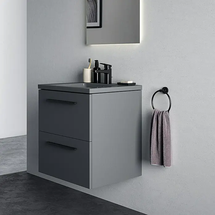 Ideal Standard Ceraplan Waschtischarmatur H90 - Schwarz, Matt, Mit Ablaufgarnitur - Modernes Badezimmer-Waschbecken mit zwei Schubladen in Grau, dazu ein Handtuchhalter und ein beleuchteter Spiegel für ein stilvolles Ambiente.