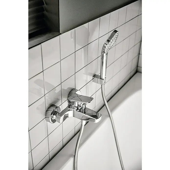 Ideal Standard Ceraplan Badewannenarmatur - Ausladung Armatur: 163 mm, Chrom, Glänzend - Nahaufnahme einer Armatur mit Brausegarnitur vor weißem Fliesenhintergrund. Elegantes Baddesign für moderne Bäder.