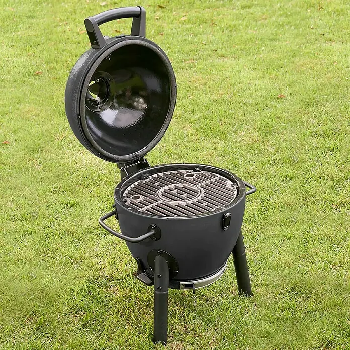 Char-Griller Holzkohlegrill Akorn Jr. Kamado - Durchmesser Grillfläche: 36 cm, Schwarz - Ein offener, schwarzer Kugelgrill auf einem Rasen. Er hat einen Griff am Deckel und seitliche Griffe am Grillkörper.