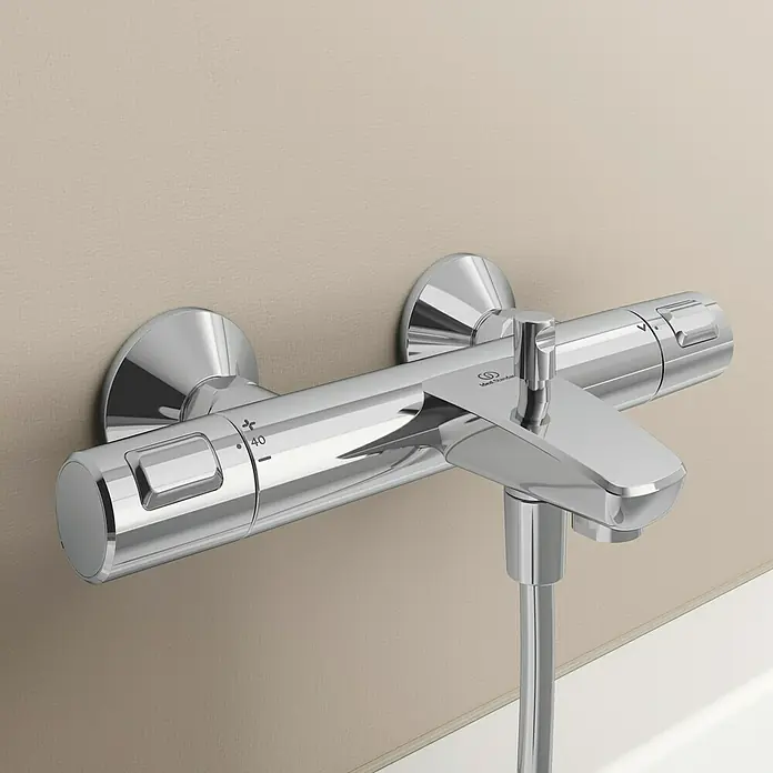 Ideal Standard Ceratherm Wannenthermostat T25Chrom, Glänzend - Nahaufnahme eines verchromten Ideal Standard Duschmischers mit Temperaturregler an einer Wand montiert.