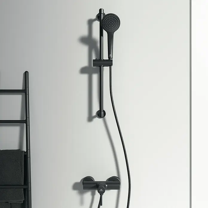 Ideal Standard Ceraline Brausearmatur - Schwarz, Matt - Bild eines schwarzen Duschsets mit Handbrause, Brausestange und Armatur vor einer hellen Wand.