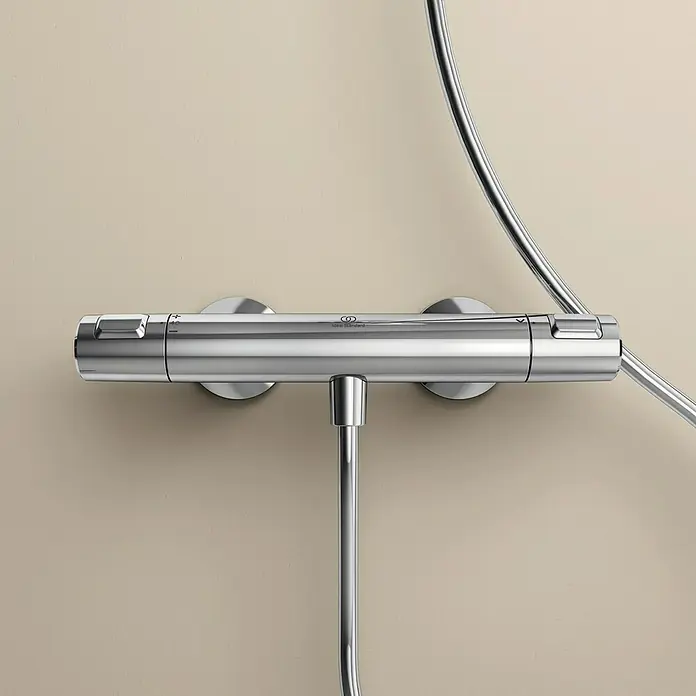 Ideal Standard Ceratherm Brausethermostat T25Chrom, Glänzend - Nahaufnahme eines Ideal Standard Duschthermostats in Chrom, das an einer beigen Wand montiert ist.