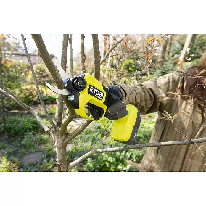 Ryobi ONE+HP Akku-Gartenschere RY18SCXA-120T - 18 V, Li-Ionen, 1 Akku, Max. Aststärke: 28 mm - Eine Person in Handschuhen benutzt eine gelb-schwarze Ryobi Akku-Astschere zum Schneiden eines Astes.