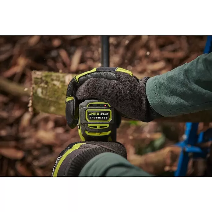 Ryobi ONE+HP Akku-Astsäge RY18PSX15A-120T - 18 V, 2 Ah, Li-Ionen, 1 Akku, Schwertlänge: 15 cm - Behandschuhte Hände halten ein grün-schwarzes Ryobi ONE+ HP Brushless Elektrowerkzeug, das Holz schneidet, mit roter LED.