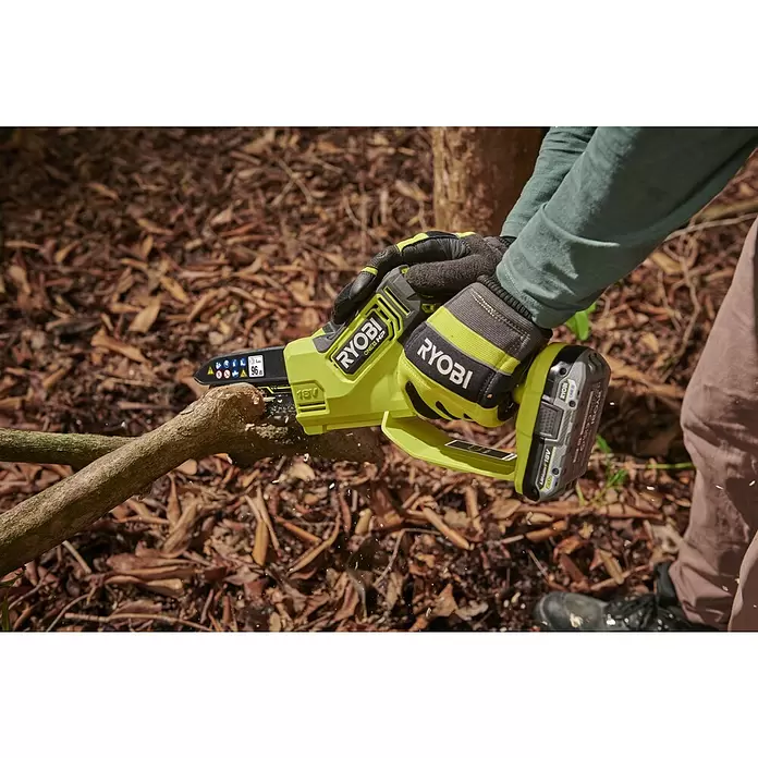 Ryobi ONE+HP Akku-Astsäge RY18PSX15A-120T - 18 V, 2 Ah, Li-Ionen, 1 Akku, Schwertlänge: 15 cm - Limo-grüne und schwarze Ryobi Kettensäge, von behandschuhten Händen gehalten, sägt einen Ast, Späne fliegen.