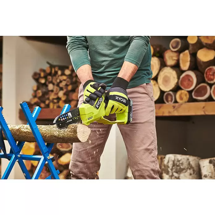 Ryobi ONE+HP Akku-Astsäge RY18PSX15A-120T - 18 V, 2 Ah, Li-Ionen, 1 Akku, Schwertlänge: 15 cm - Person schneidet mit einer limettengrünen und schwarzen Ryobi Akku-Kettensäge ein Holzscheit auf einem blauen Sägebock.