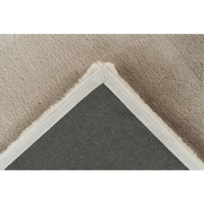 Fellteppich Happy - Light Taupe, 170 x 120 cm, 100 % Polyester (Flor) - Detailaufnahme eines flauschigen Teppichs mit grauem Flor, der eine weiche Textur und eine robuste Unterseite zeigt.
