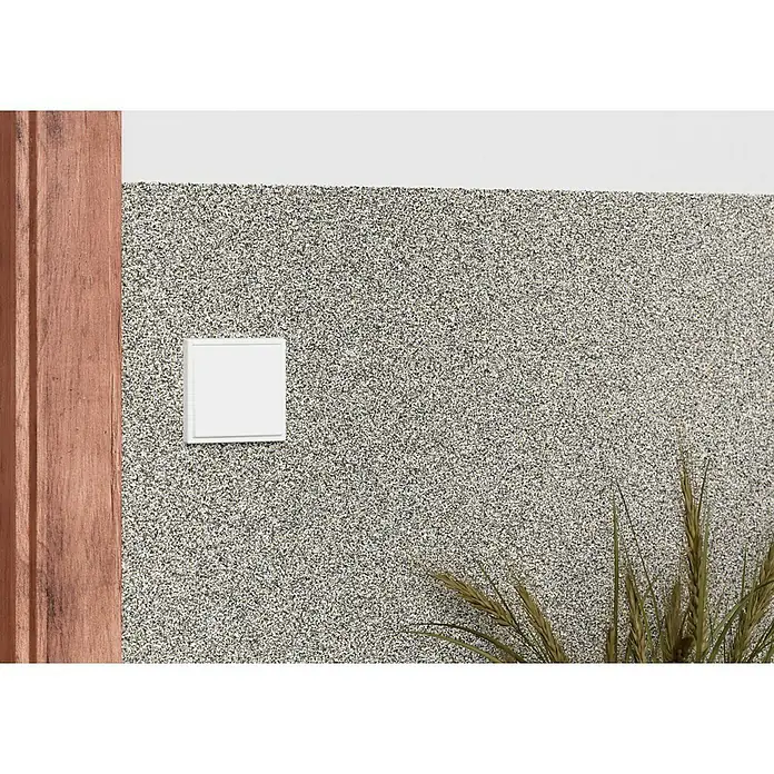 swingcolor Buntsteinputz - Korngröße: 2 - 3 mm, 20 kg, Nr. 51 - Nahaufnahme einer weißen quadratischen Steckdose an einer gesprenkelten Wand, neben einem braunen Holzrahmen und einer grünen Pflanze.