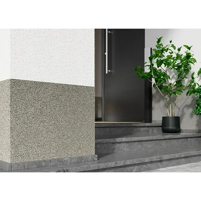 swingcolor Buntsteinputz - Korngröße: 2 - 3 mm, 20 kg, Nr. 51 - Nahaufnahme eines Hauses mit einem Fassadensockel aus Naturstein, der einen stilvollen Übergang zur weißen Fassade bildet.