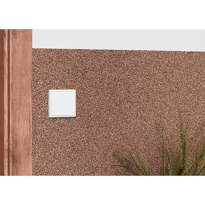 swingcolor Buntsteinputz - Korngröße: 2 - 3 mm, 20 kg, Nr. 52 - Detailansicht einer weißen, quadratischen Schalterabdeckung an einer Wand mit Textur, neben einem Holzrahmen.