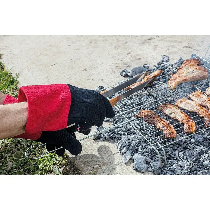 Juba Guante para barbacoa H295 Garden - Textil, Negro/Rojo - Una mano con un guante de parrilla usa unas pinzas para dar la vuelta a la carne en una parrilla, lista para disfrutar al aire libre.