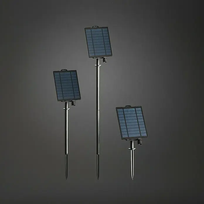 Konstsmide Solar-Batteriebox - 2,5 x 11 x 14 cm - Drei Solarpanels mit Erdspieß stehen vor einem grauen Hintergrund. Diese Solarpanels sind ideal für den Garten und laden sich mit Sonnenenergie auf.
