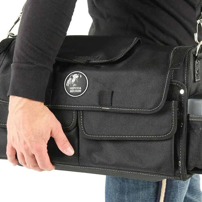 Hepco & Becker Werkzeugtasche Profi-Installateurtasche 5858 - L x B x H: 200 x 400 x 240 mm, Polyester - Nahaufnahme einer schwarzen Hepco & Becker Werkzeugtasche, die von einer Person gehalten wird, ideal für Motorradfahrer und Werkstattarbeiten.
