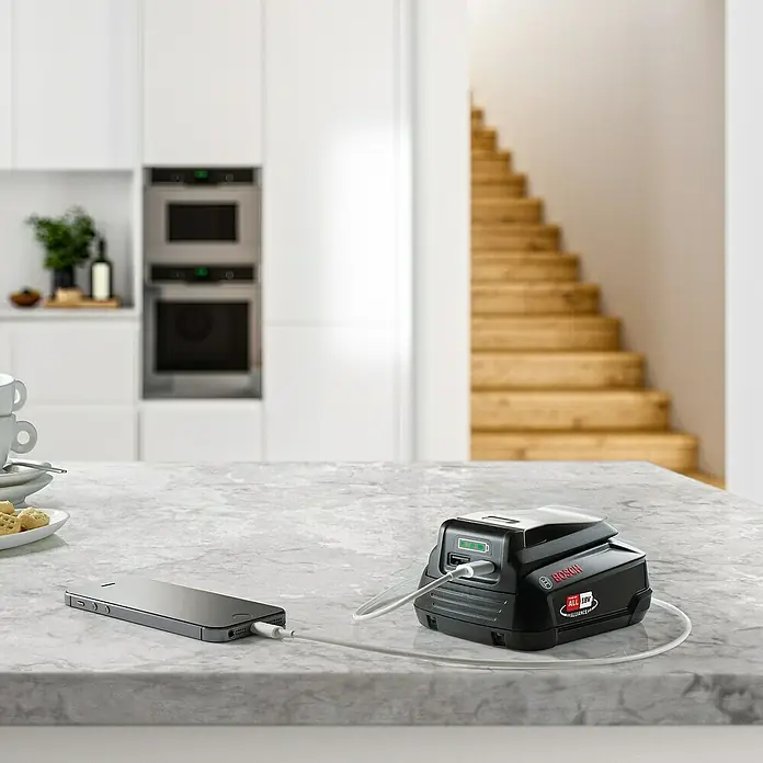 Bosch USB-Adapter Universal USB 18V-45 - Passend für: Power for All 18V Akkus - Ein Bosch-Akkuadapter lädt ein Smartphone auf einer Küchentheke auf, ein praktisches Gerät für unterwegs.