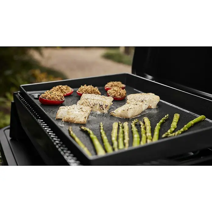 Weber Plancha-Grill Slate GP 56 - Grillfläche (B x T): 56 x 41 cm, 4,7 kW, Anzahl Brenner: 2 Stk. - Auf einem schwarzen Grill werden Fisch, Spargel und gefüllte Tomaten zubereitet. Der Grill ist der Star dieser köstlichen Mahlzeit im Freien.