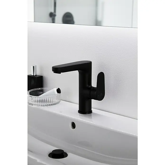 Ideal Standard Cerafine O Waschtischarmatur H155 - Schwarz, Matt, Ohne Ablaufgarnitur - Elegante Nahaufnahme eines schwarzen Wasserhahns auf einem weißen Waschbecken, akzentuiert durch stilvolle Badaccessoires.