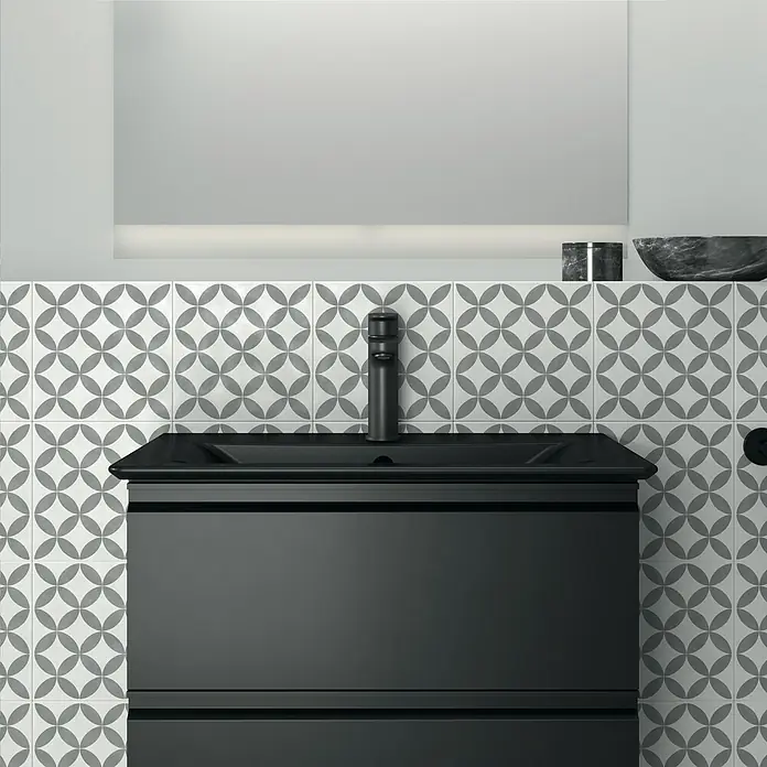 Ideal Standard Connect Air Einbauwaschbecken - 64 x 46 cm, Ohne Spezialglasur, Hahnloch: Mitte, Mit Überlauf, Schwarz - Nahaufnahme eines stilvollen Badezimmers mit einem schwarzen Waschtischunterschrank und einem modernen Wasserhahn vor gemusterten Fliesen.