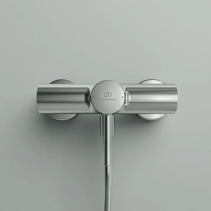 Ideal Standard Ceraline Brausearmatur - Chrom, Glänzend - Nahaufnahme eines Ideal Standard Duschmischers aus Chrom, der an einer grauen Wand montiert ist. Das elegante Design wertet jedes Badezimmer auf.
