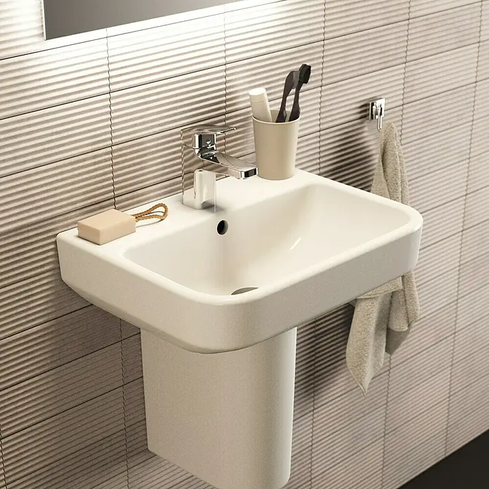 Ideal Standard i.life S Waschtisch - 50 x 38 cm, Ohne Spezialglasur, Hahnloch: Mitte, Mit Überlauf, Weiß - Nahaufnahme eines modernen weißen Waschbeckens mit Armatur, Seife und Zahnbürste im Badezimmer.