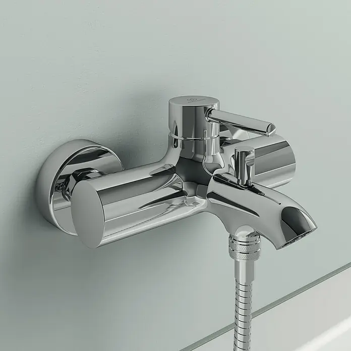 Ideal Standard Ceraline BadewannenarmaturChrom, Glänzend - Nahaufnahme eines glänzenden Chrom-Wasserhahns mit Brauseschlauch an einer Badezimmerwand, der ein elegantes und modernes Design zeigt.