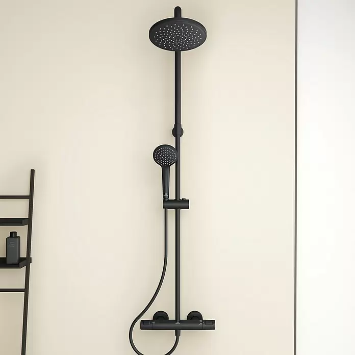 Ideal Standard Ceratherm Sistema de ducha - Con grifería termostática, Altura: 103 cm, Número de tipos de chorro: 1 ud., Negro - Sistema de ducha negro con rociador y teleducha, mezclador termostático, en pared crema en un baño.