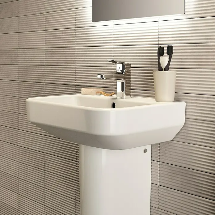 Ideal Standard i.life S Waschtisch - 50 x 38 cm, Ohne Spezialglasur, Hahnloch: Mitte, Mit Überlauf, Weiß - Waschbecken mit Armatur und horizontalen Fliesen im Hintergrund.