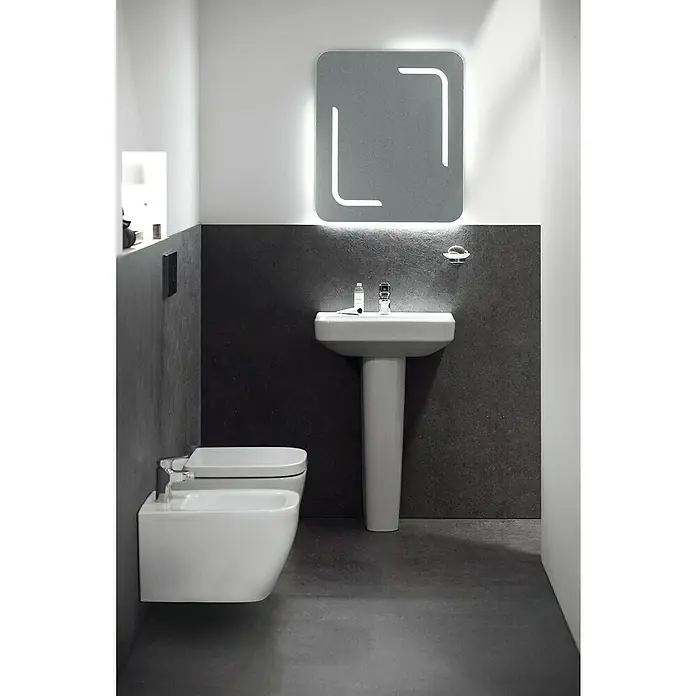 Ideal Standard i.life S Waschtisch - 55 x 38 cm, Ohne Spezialglasur, Hahnloch: Mitte, Mit Überlauf, Weiß - Badezimmer mit weißem Waschbecken und Toilette vor einer grauen Wand mit beleuchtetem Spiegel. Elegantes Design für moderne Bäder.
