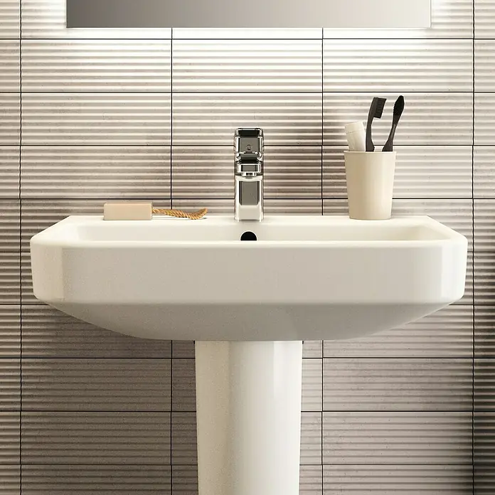 Ideal Standard i.life S Waschtisch - 60 x 38 cm, Ohne Spezialglasur, Hahnloch: Mitte, Mit Überlauf, Weiß - Nahaufnahme eines Waschbeckens mit Armatur, Seife und Zahnbürsten vor einem gefliesten Hintergrund.