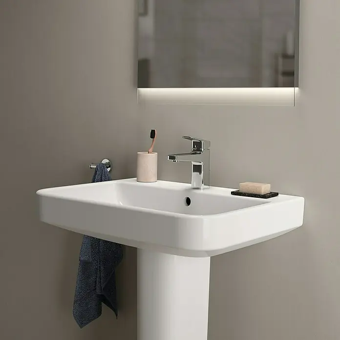 Ideal Standard i.life B Waschtisch - 65 x 48 cm, Ohne Spezialglasur, Hahnloch: Mitte, Mit Überlauf, Weiß - Elegantes Waschbecken mit klaren Linien, komplett mit Armatur, Seife und Handtuch, unter einem modernen Spiegel mit Beleuchtung.