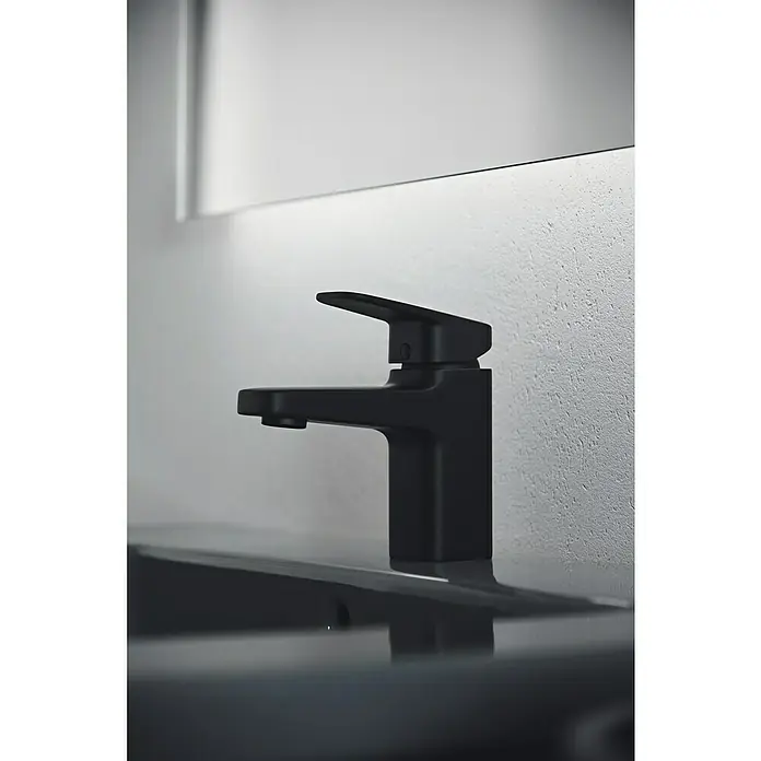 Ideal Standard Ceraplan Waschtischarmatur H75 - Schwarz, Matt - Nahaufnahme einer eleganten, mattschwarzen Armatur auf einem dunklen Waschtisch, vor einer hellen Wand und einem Spiegel.