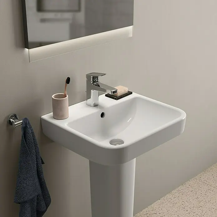 Ideal Standard i.life B Waschtisch - 50 x 44 cm, Ohne Spezialglasur, Hahnloch: Mitte, Mit Überlauf, Weiß - Nahaufnahme eines modernen Waschbeckens mit Armatur, Seife und Zahnputzbecher im Badezimmer.