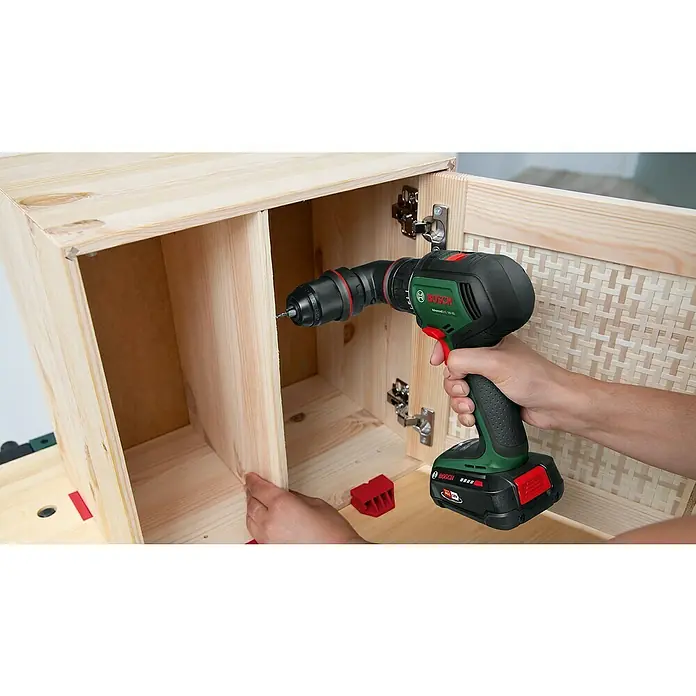 Bosch Power for All 18V Akku-Bohrschrauber AdvancedDrill 18V-80 QuickSnap - 18 V, Ohne Akku, 78 Nm, 3 Aufsätze - Ein Mann befestigt ein Scharnier an einem hölzernen Schrank mit einem Bosch Akku-Bohrschrauber, um ein Möbelstück zusammenzubauen.