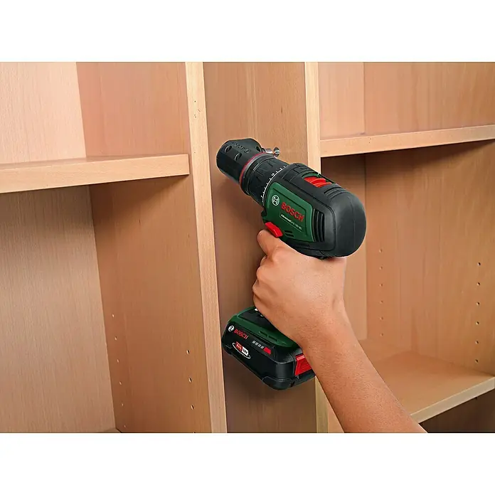 Bosch Power for All 18V Akku-Bohrschrauber AdvancedDrill 18V-80 QuickSnap - 18 V, 1 Akku, 2,5 Ah, 78 Nm - Ein Bosch Akku-Bohrschrauber wird verwendet, um ein Regal in einem Holzschrank zu befestigen. Das Werkzeug ist grün, schwarz und rot.