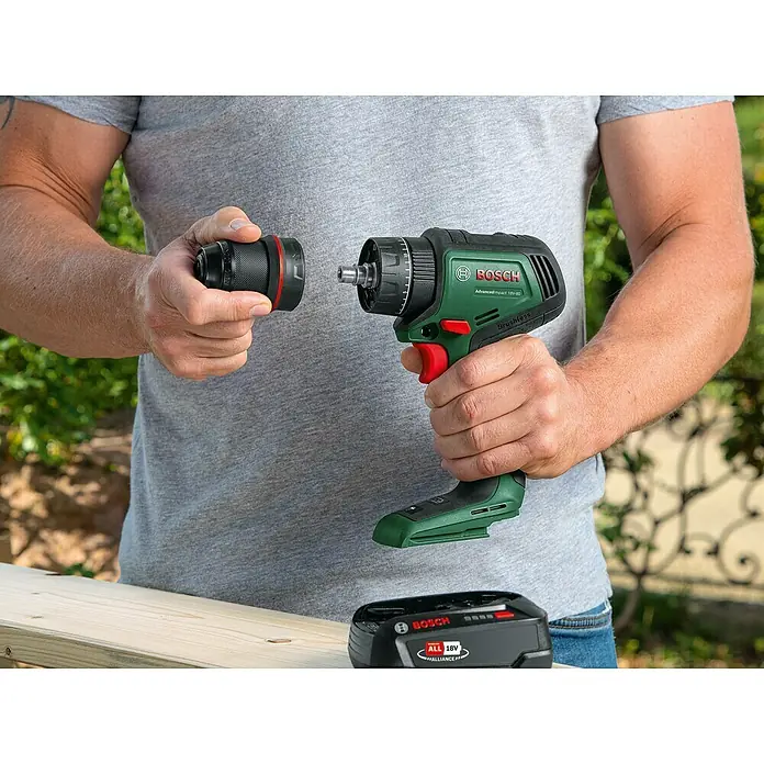 Bosch Power for All 18V Akku-Schlagbohrschrauber Advanced Impact 18V-80 QuickSnap - 18 V, Ohne Akku, 82 Nm, 3 Aufsätze - Ein Mann befestigt einen Aufsatz an einem grünen Bosch Akku-Bohrschrauber AdvancedImpact 18V-80.