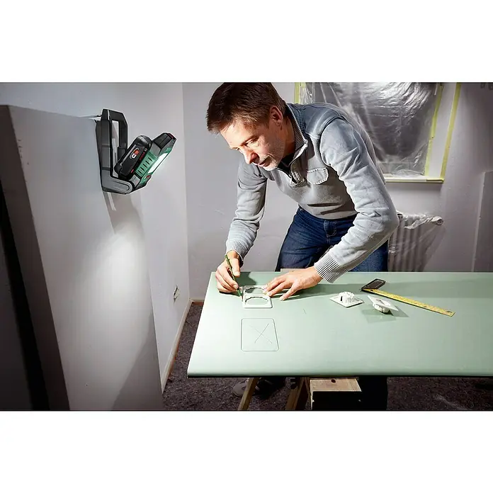 Bosch Power for All 18V Akku-Lampe UniversalWorkLight 18V-2100 - 18 V, Ohne Akku, 3 Helligkeitsstufen - Mann zeichnet mit dem Bosch Professional GLI 18V-1900 Akku-Baustrahler eine Form auf eine grüne Oberfläche.