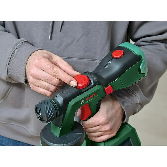 Bosch Power for All 18V Akku-Farbsprühsystem AdvancedSpray 18V-500 - 18 V, Ohne Akku, Max. Fördermenge: 500 l/h - Ein Mann justiert eine Bosch AdvancedSpray MV-600 Farbspritzpistole mit roten Einstellknöpfen.