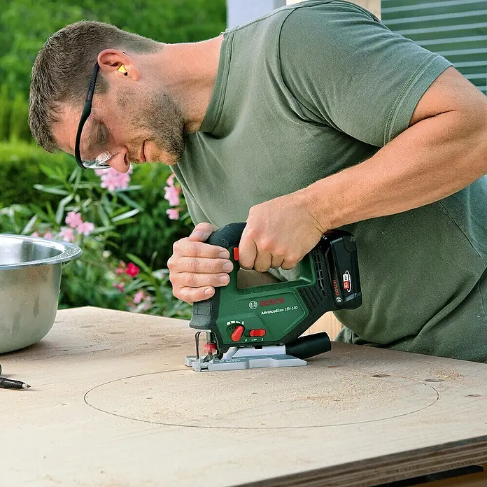 Bosch Power for All 18V Akku-Stichsäge Advanced Saw 18V-140 - 18 V, Ohne Akku, Leerlaufhubzahl: 3.000 /min - Ein Mann sägt mit einer Bosch AdvancedSaw 18V-140 Stichsäge ein Loch in eine Holzplatte.