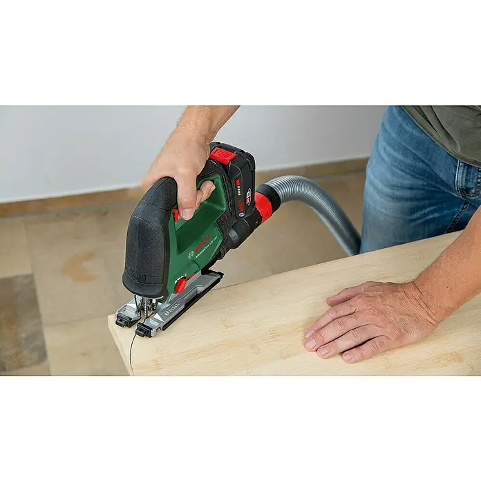Bosch Power for All 18V Akku-Stichsäge Advanced Saw 18V-140 - 18 V, Ohne Akku, Leerlaufhubzahl: 3.000 /min - Der Bosch AdvancedSaw 18V-140 Akku-Stichsäge mit Staubabsaugung im Einsatz, präzise Kurven auf Holz schneidend.
