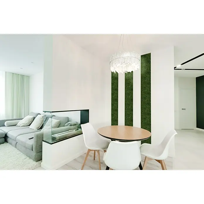 Jangal Wandpaneel Modular Wall Moos - Dark Green, 520 x 520 x 30 mm - Ein modernes Esszimmer mit einem runden Holztisch, weißen Stühlen und einer stilvollen Kristallleuchte, akzentuiert durch grüne Wandelemente.