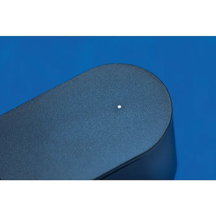 Abus Steuerzentrale BRIDGE ONE CFW3100BK - Schwarz, B x H: 55 x 52 mm - Nahaufnahme eines schwarzen Geräts mit einer kleinen, hellen LED-Anzeige auf einer blauen Oberfläche. Das Gerät hat eine abgerundete Form.