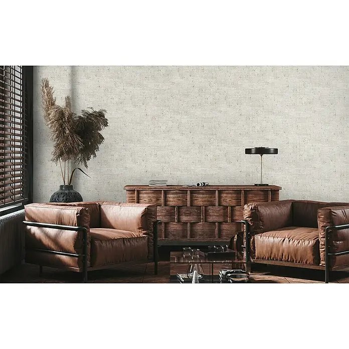 A.S. Création Stories of Life Vliestapete - Grau-Cremeweiß-Gold, Uni, 10,05 x 0,53 m - Wohnzimmer-Interieur mit braunen Ledersesseln und einem Holzschrank, beleuchtet durch eine elegante Lampe. Der Raum strahlt Wärme und Komfort aus.