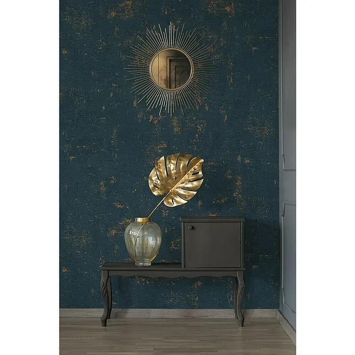 A.S. Création Jade 2 Vliestapete - Dunkelblau-Gold, Uni, 10,05 x 0,53 m - Stilvolles Interieur mit einem dekorativen Spiegel, einer goldenen Monstera-Pflanze und einem eleganten Schrank auf einem dunklen Tisch.