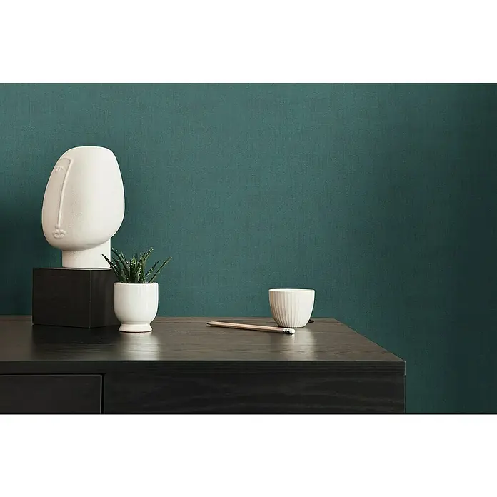 A.S. Création Jade 2 Vliestapete - Petrol, Uni, 10,05 x 0,53 m - Nahaufnahme einer modernen Tischdekoration mit einem stilvollen Gesichtsvase, einer kleinen Pflanze und einer schlichten Tasse auf dunklem Holz.