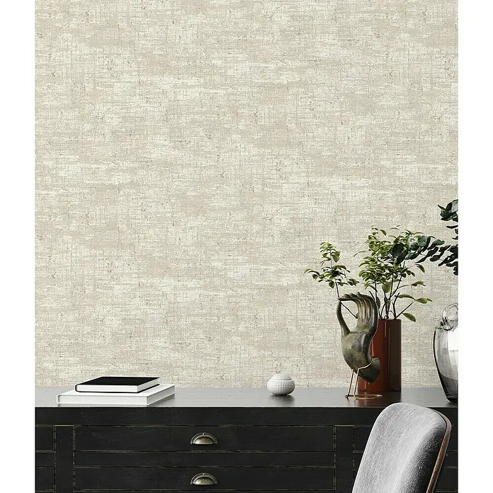 A.S. Création Stories of Life Vliestapete - Beige-Weiß-Gold, Uni, 10,05 x 0,53 m - Ein interner Hintergrund mit strukturiertem sandfarbenem Uni-Tapetenmuster, das die Oberfläche auf der Kommode hervorhebt.