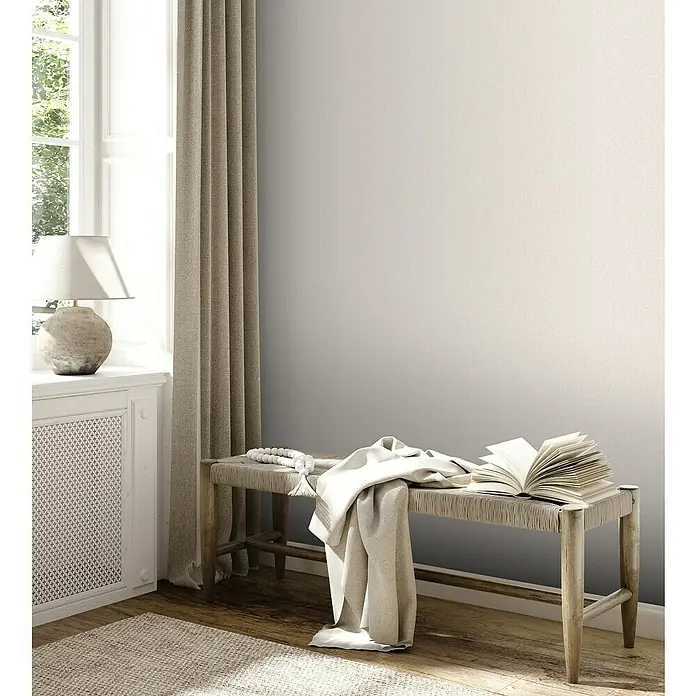 A.S. Création Jade 2 Vliestapete - Creme-Weiß, Uni, 10,05 x 0,53 m - Elegante Inneneinrichtung mit einer stilvollen Holzbank, dekoriert mit einem Buch und einer sanften Decke, die eine ruhige Atmosphäre schafft.