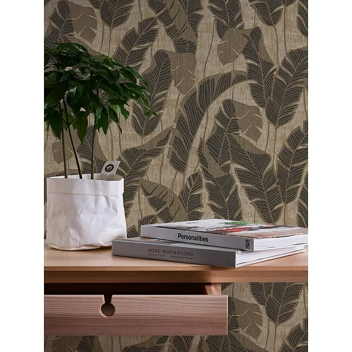 A.S. Création Jade 2 Vliestapete Blätter - Schwarzbeige, Floral, 10,05 x 0,53 m - Nahaufnahme von einem Schreibtisch mit einer Pflanze und zwei Büchern vor einer floralen Tapete.