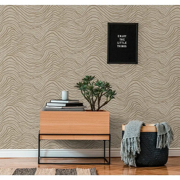 A.S. Création Jade 2 Vliestapete - Beige-Gold-Grau, 3D-Optik, 10,05 x 0,53 m - Nahaufnahme eines Raumes mit gemusterter Tapete, einem Pflanzgefäß, Büchern und einer dekorativen Tafel.