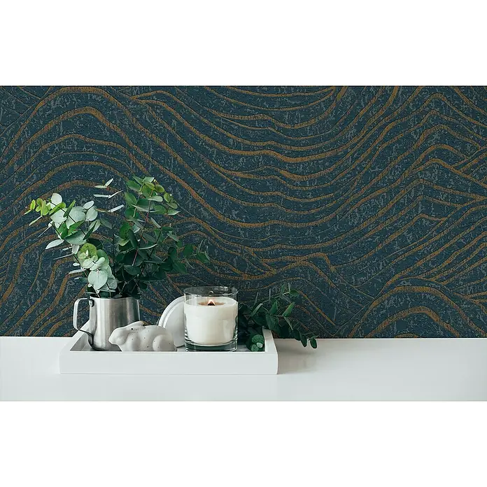 A.S. Création Jade 2 Vliestapete - Dunkelblau-Gold, 3D-Optik, 10,05 x 0,53 m - Elegante Dekoration mit einer Kerze, einem kleinen Hasen und einem silbernen Krug auf einem weißen Tablett vor einer gemusterten Wand.