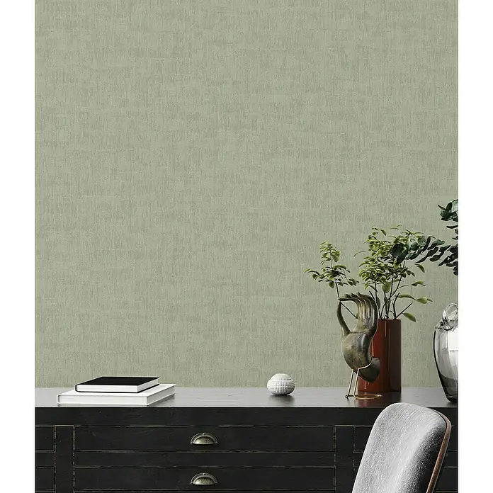 A.S. Création Jade 2 Vliestapete - Grün, Uni, 10,05 x 0,53 m - Nahaufnahme eines Tisches mit Dekorationselementen, darunter Bücher und Pflanzen.