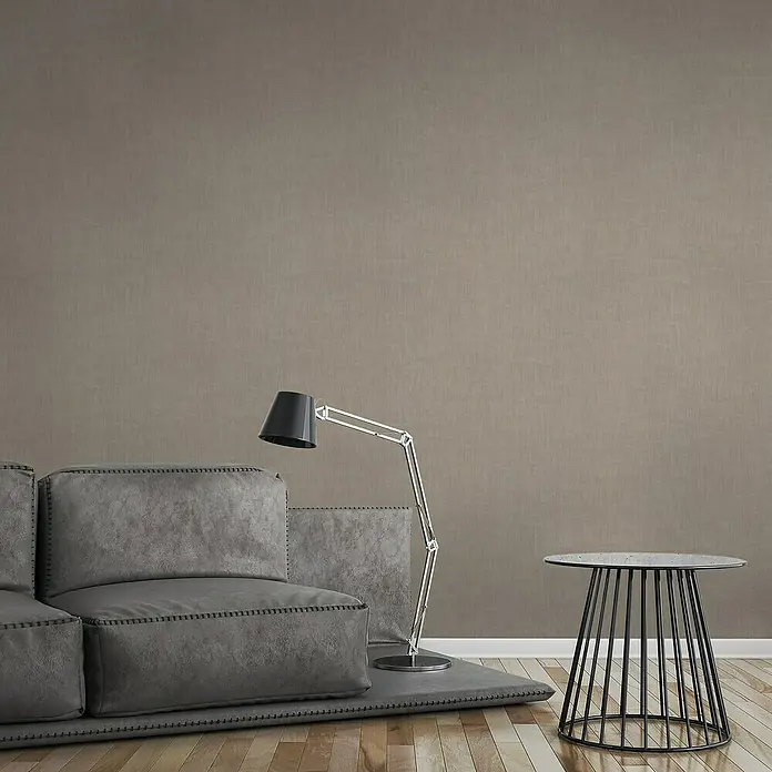 A.S. Création Jade 2 Vliestapete - Braungrau, Uni, 10,05 x 0,53 m - Modernes Wohnzimmer-Interieur mit grauem Sofa, Stehlampe und Beistelltisch auf hellem Holzboden. Elegantes Design für Wohnräume.